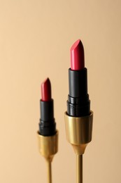 Beautiful glossy pink and red lipsticks on beige background
