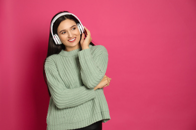 Photo of Young woman listening to audiobook on pink background. Space for text