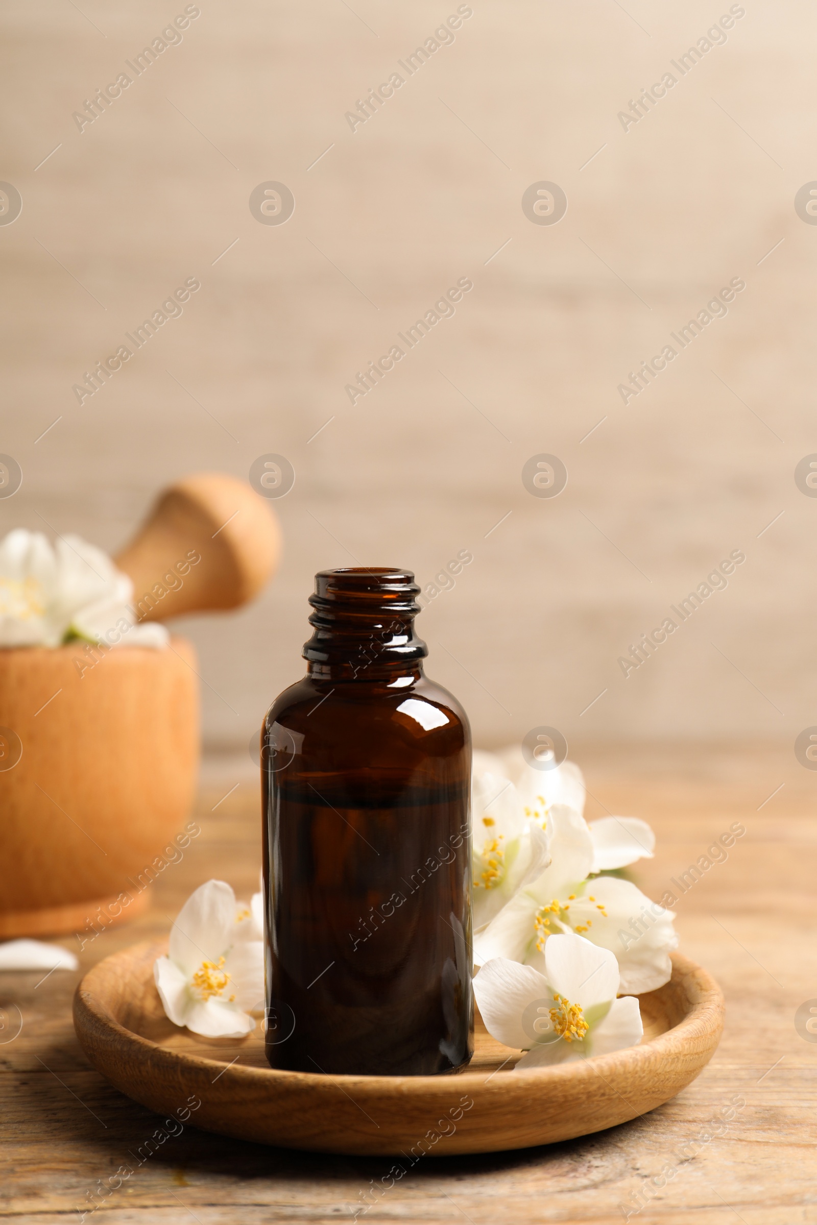 Photo of Jasmine essential oil and fresh flowers on wooden table