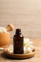 Jasmine essential oil and fresh flowers on wooden table