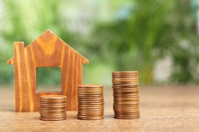 Photo of Mortgage concept. House model and stacks of coins on wooden table against blurred green background