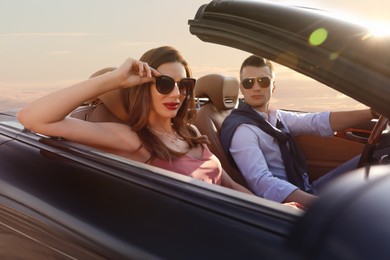 Photo of Stylish couple driving luxury convertible car outdoors