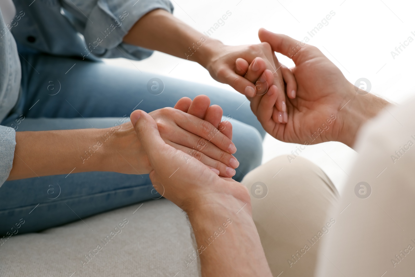 Photo of Religious people holding hands and praying together indoors, closeup