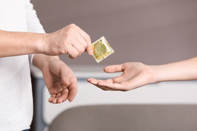 Photo of Father giving condom to his teenage son indoors, closeup. Sex education concept