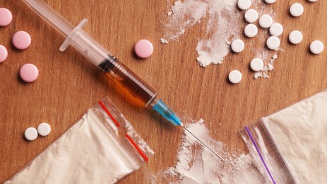 Photo of Different hard drugs on wooden table, flat lay