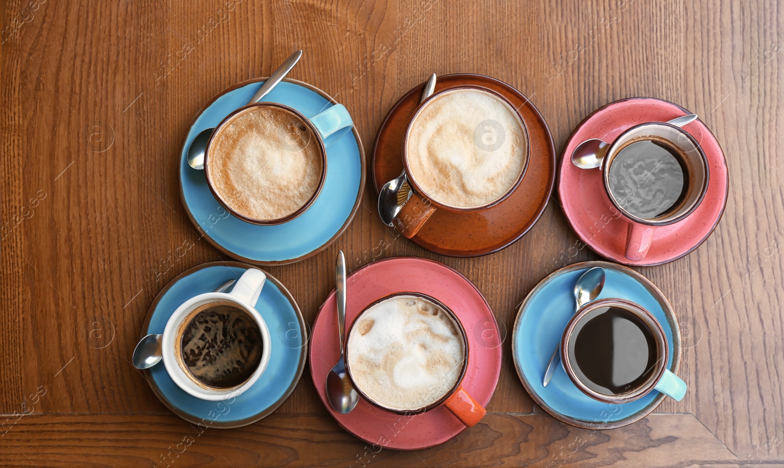 Photo of Cups of fresh aromatic coffee on wooden table, top view