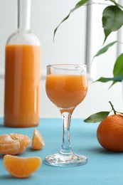 Delicious tangerine liqueur and fresh fruits on light blue wooden table