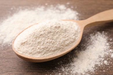 Spoon with quinoa flour on wooden table, closeup