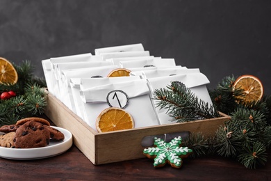 Paper bags, cookies and fir branches on wooden table. Christmas advent calendar
