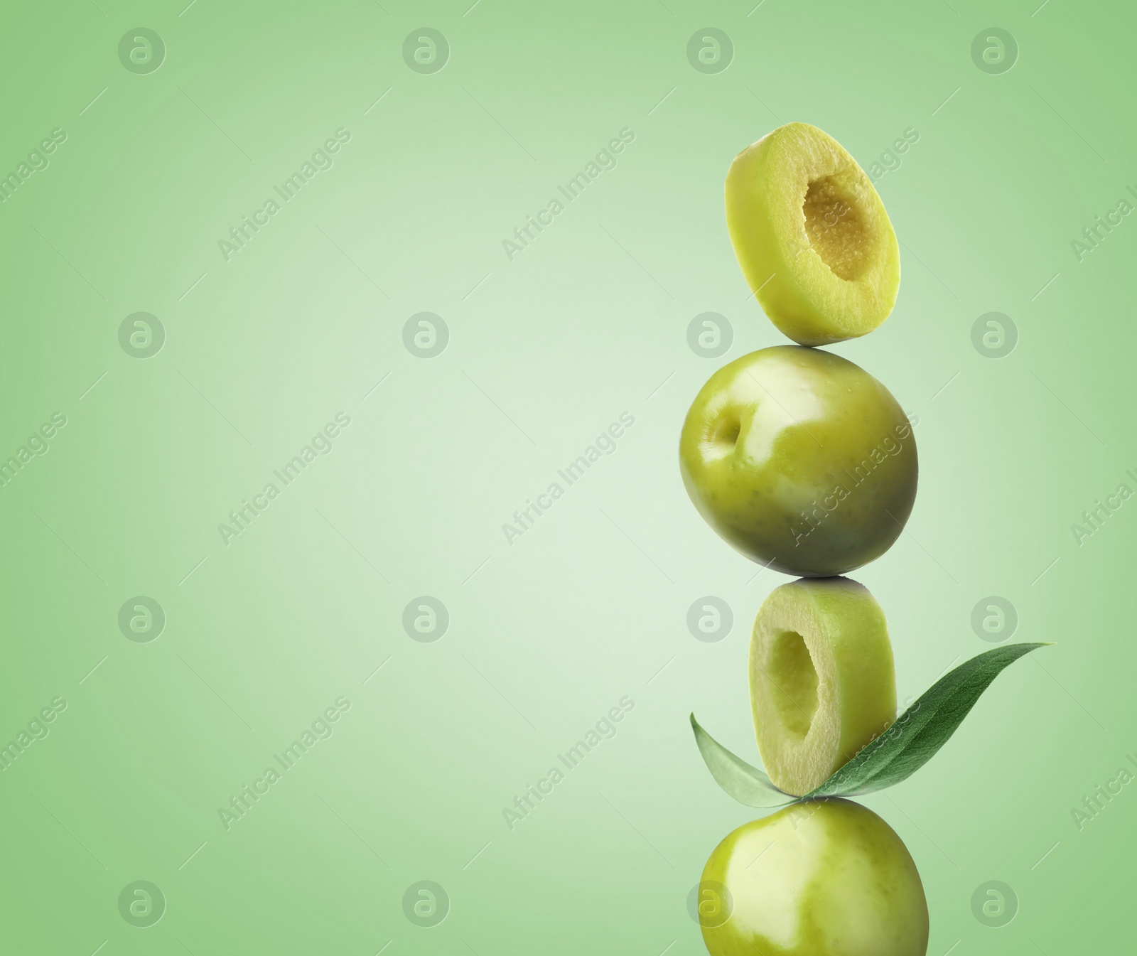 Image of Cut and whole olives with leaf on light green background, space for text