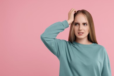 Portrait of embarrassed young woman on pink background, space for text