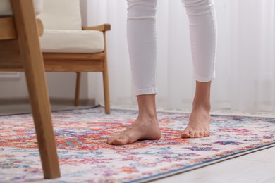 Woman standing on carpet with pattern at home, closeup