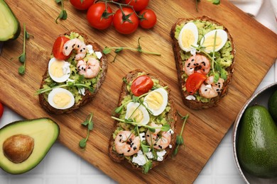 Delicious sandwiches with guacamole, shrimps and tomatoes on white table, flat lay