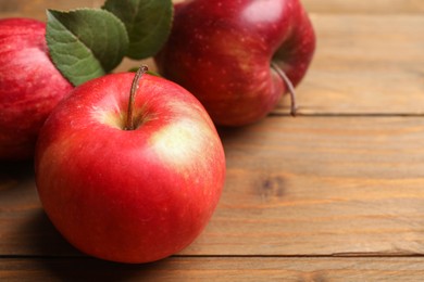 Photo of Fresh red apples on wooden table, closeup. Space for text