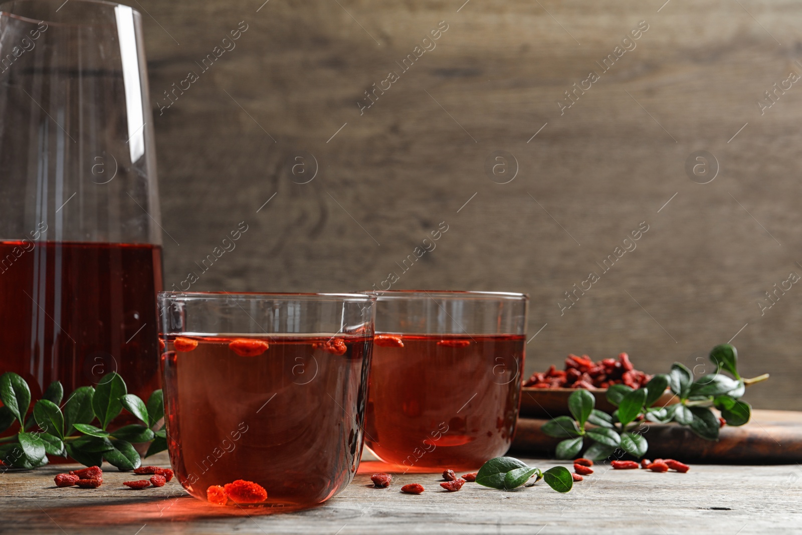 Photo of Healthy goji juice on wooden table. Space for text