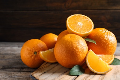 Fresh oranges with leaves on wooden table