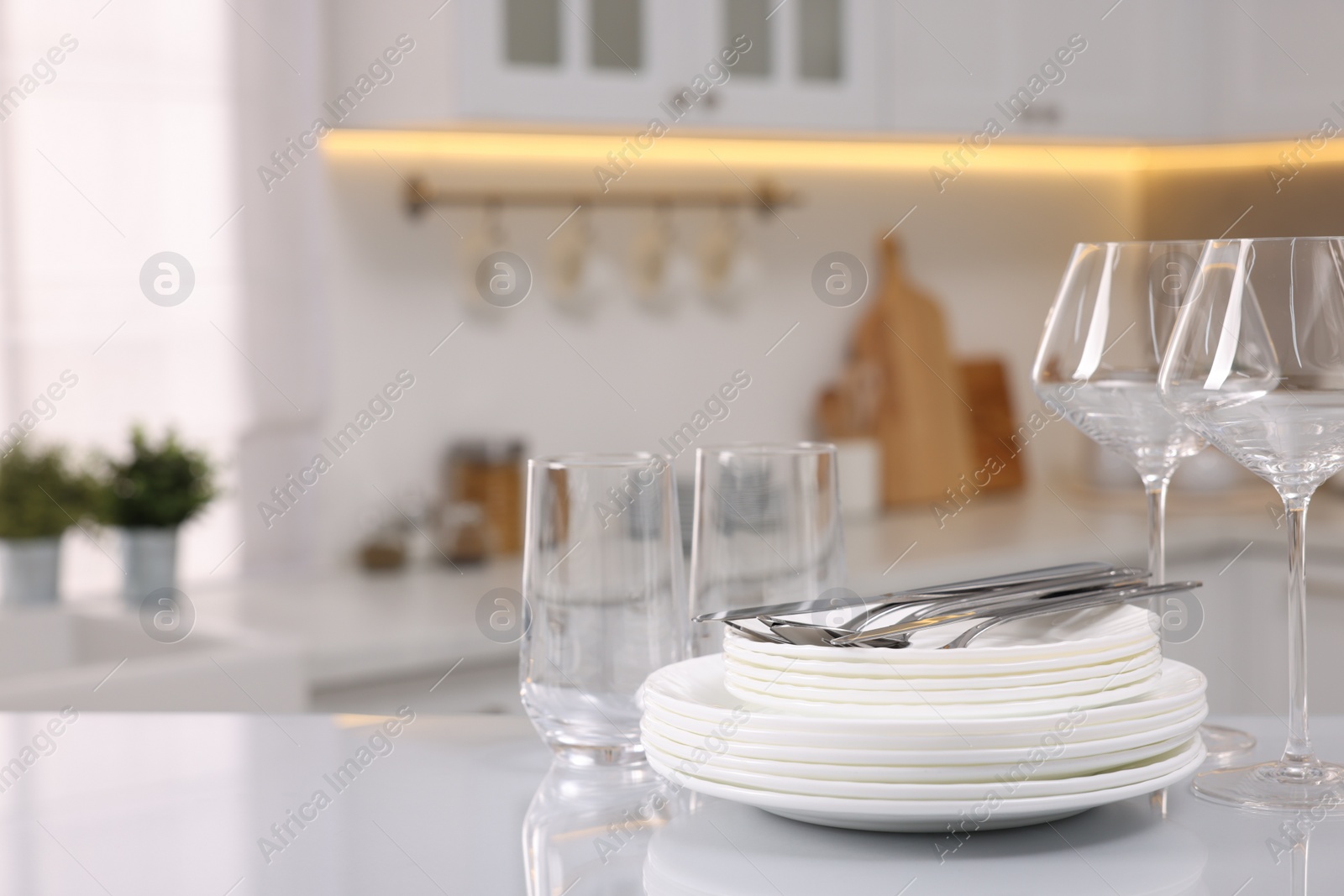 Photo of Set of clean dishware, glasses and cutlery on table in kitchen, space for text