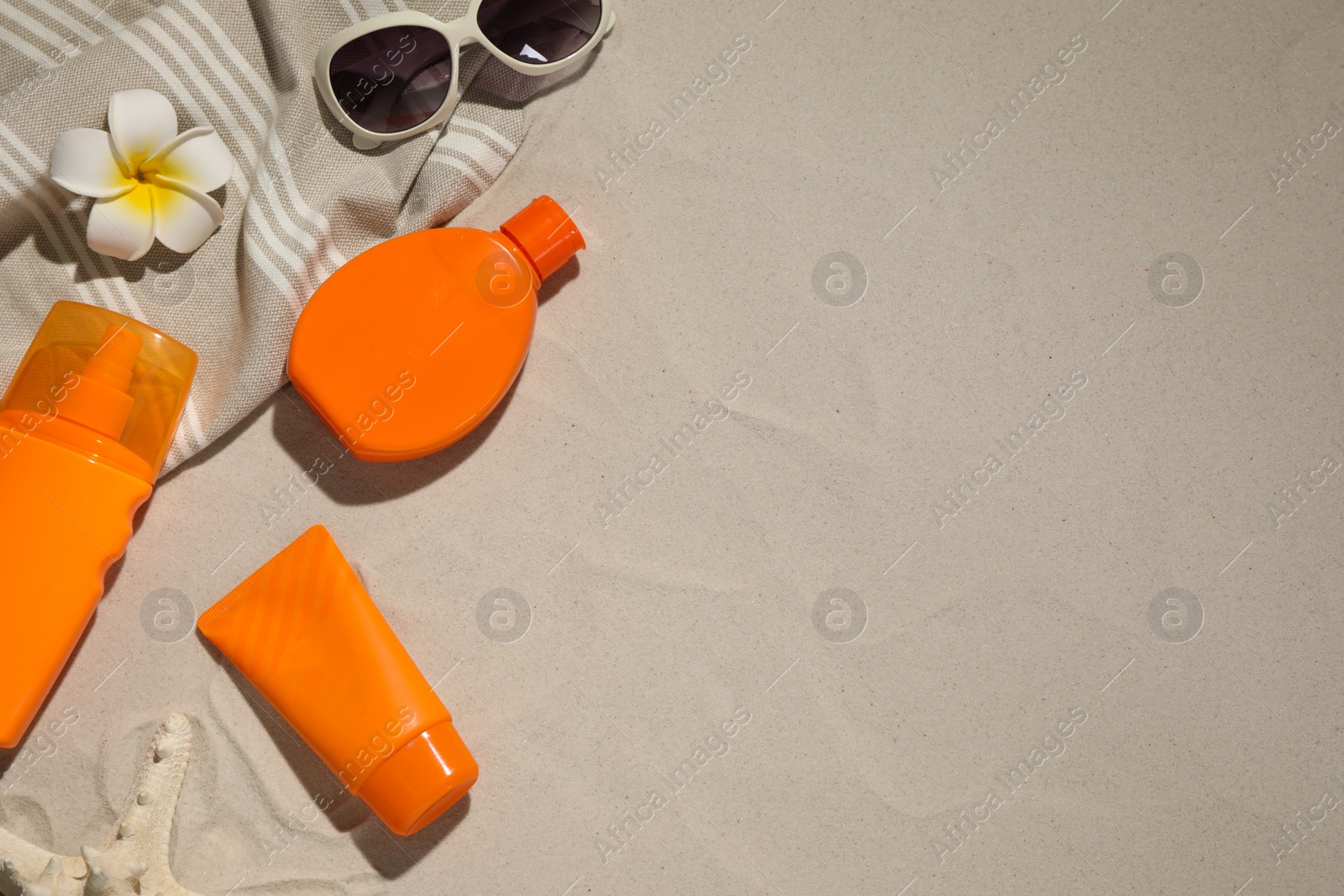 Photo of Flat lay composition with sun protection products on sand. Space for text