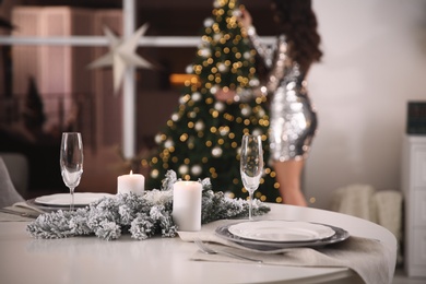 Photo of Woman decorating Christmas tree at home, focus on festive table setting