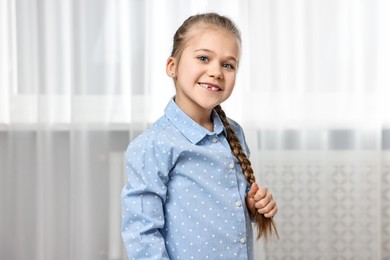 Photo of Cute little girl with braided hair indoors