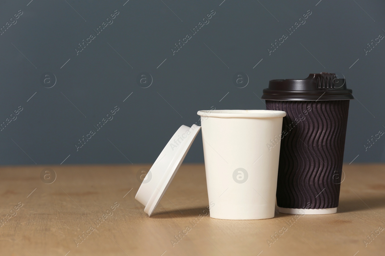 Photo of Cardboard cups of coffee on table against grey background. Space for text
