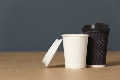 Cardboard cups of coffee on table against grey background. Space for text