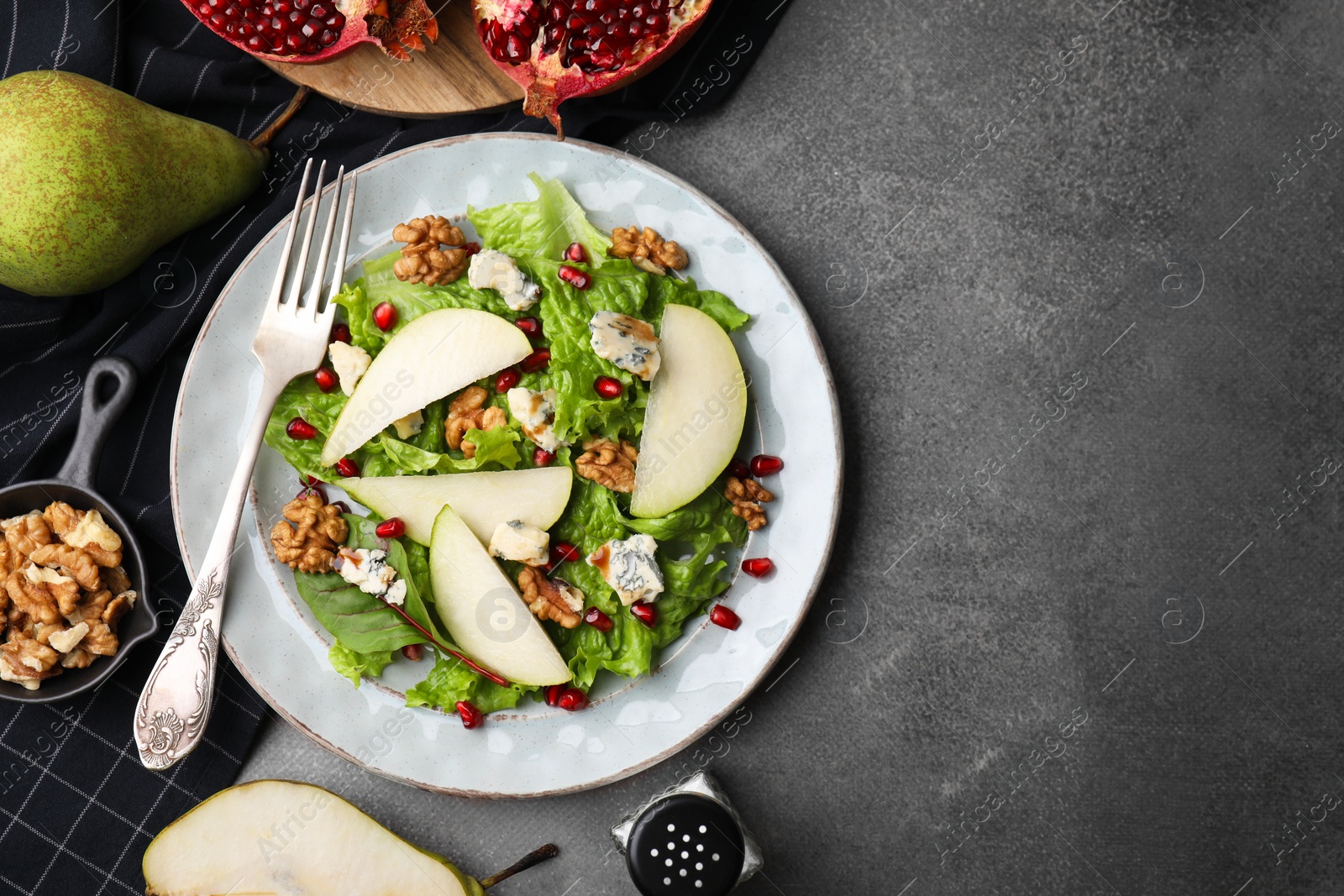 Photo of Delicious pear salad served on dark textured table, flat lay. Space for text