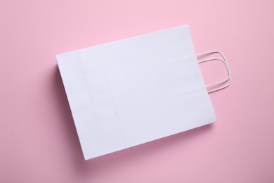 Photo of White paper bag on pink background, top view. Space for text