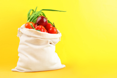 Photo of Cotton eco bag with vegetables on yellow background. Space for text