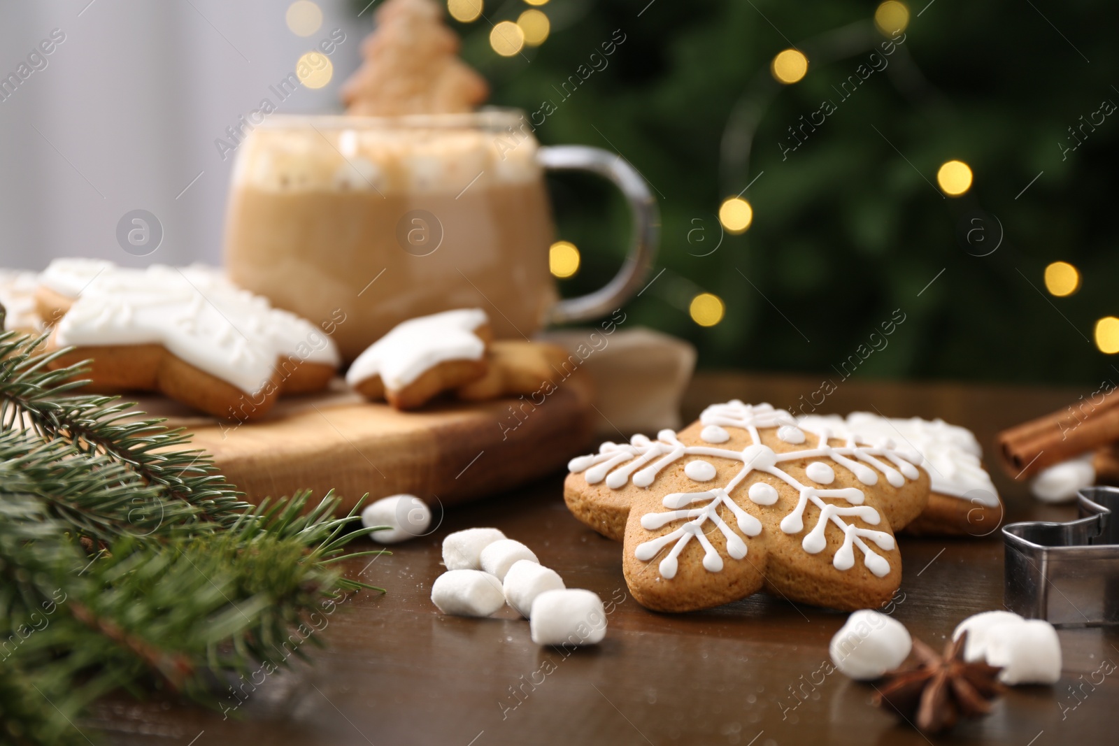 Photo of Decorated cookies on table against blurred Christmas lights, closeup