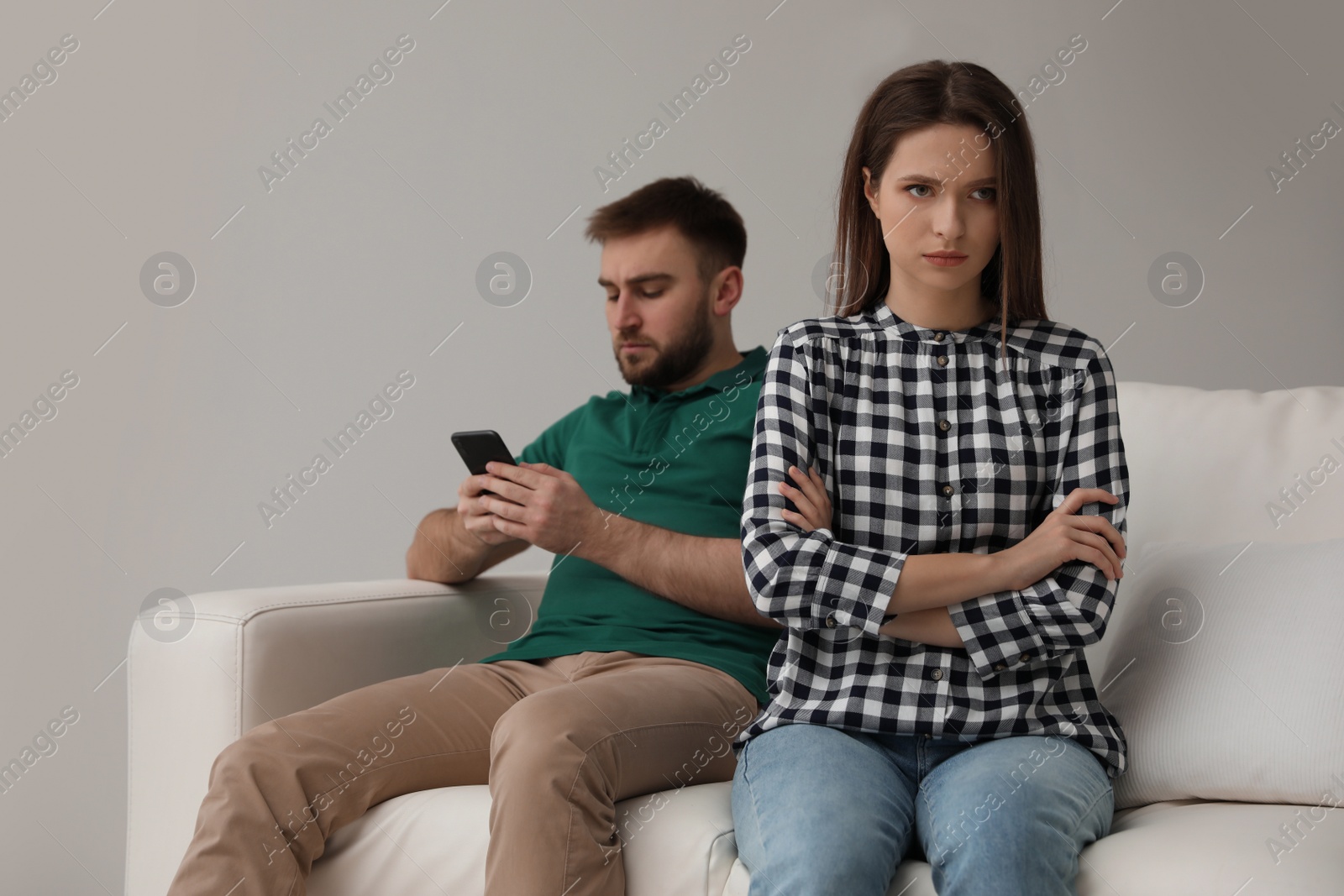 Photo of Young man preferring smartphone over his girlfriend at home. Relationship problems