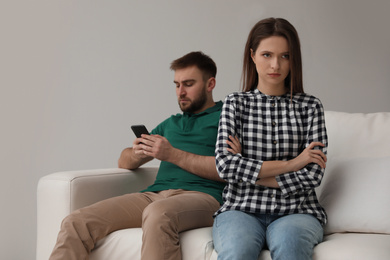 Young man preferring smartphone over his girlfriend at home. Relationship problems