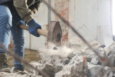 Man breaking stones with sledgehammer outdoors, closeup