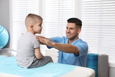 Photo of Orthopedist examining child in clinic. Scoliosis treatment