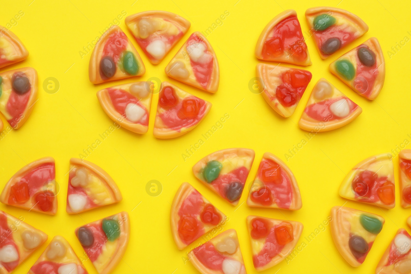 Photo of Tasty jelly candies in shape of pizza on yellow background, flat lay