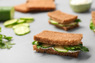 Photo of Traditional English cucumber sandwiches on grey table