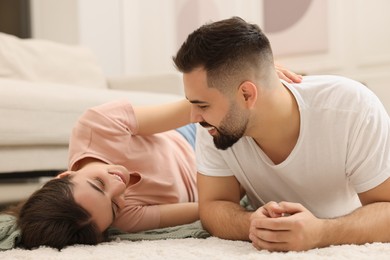 Photo of Affectionate young couple spending time together on soft carpet at home