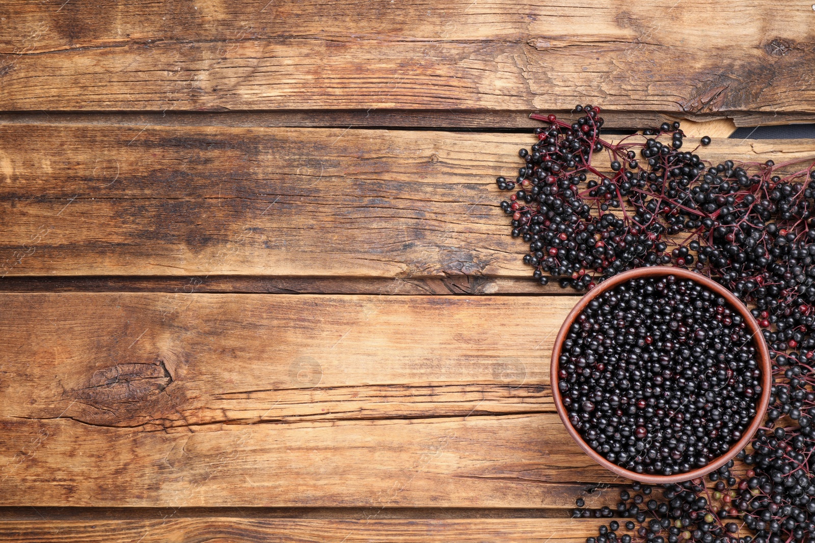 Photo of Elderberries (Sambucus) on wooden table, flat lay. Space for text