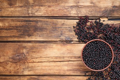 Photo of Elderberries (Sambucus) on wooden table, flat lay. Space for text