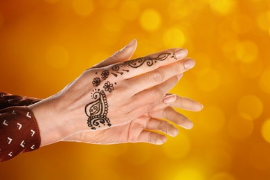 Image of Woman with henna tattoo on hand against blurred lights, bokeh effect