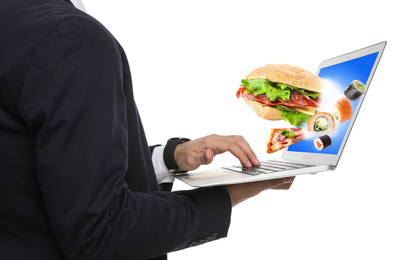 Man using laptop for ordering food online on white background, closeup. Delivery service during quarantine
