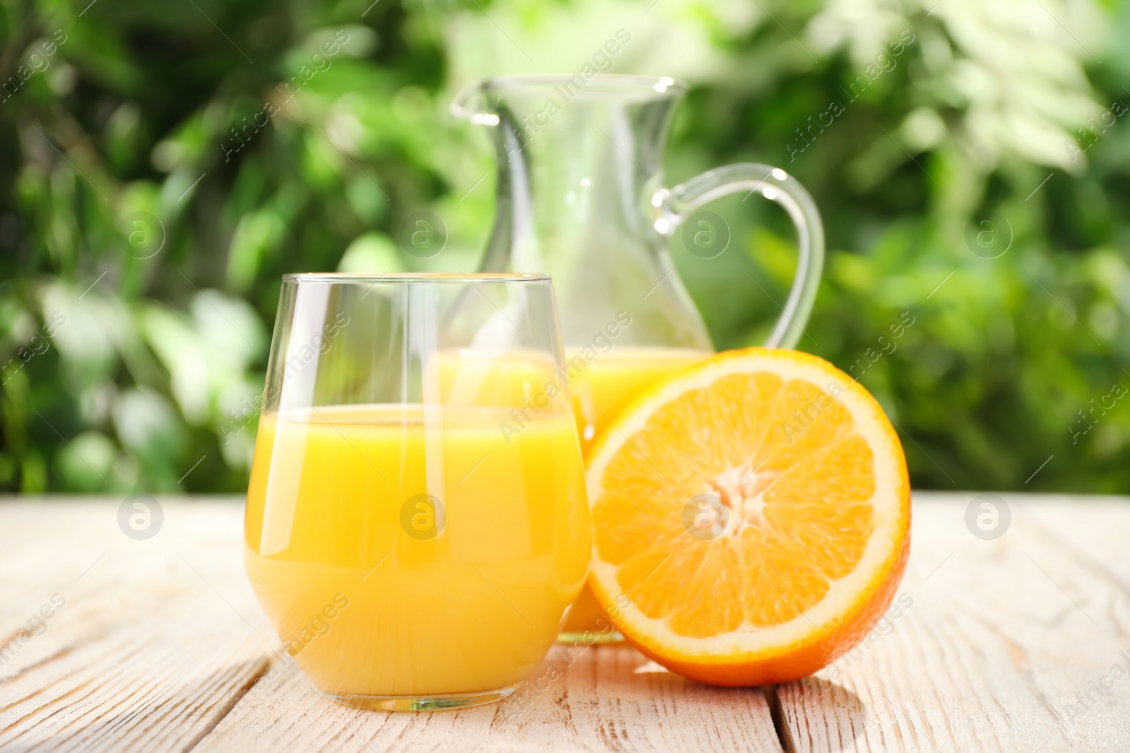 Photo of Glassware of fresh orange juice on white wooden table