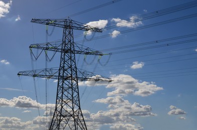 Photo of High voltage tower with electricity transmission power lines against blue sky