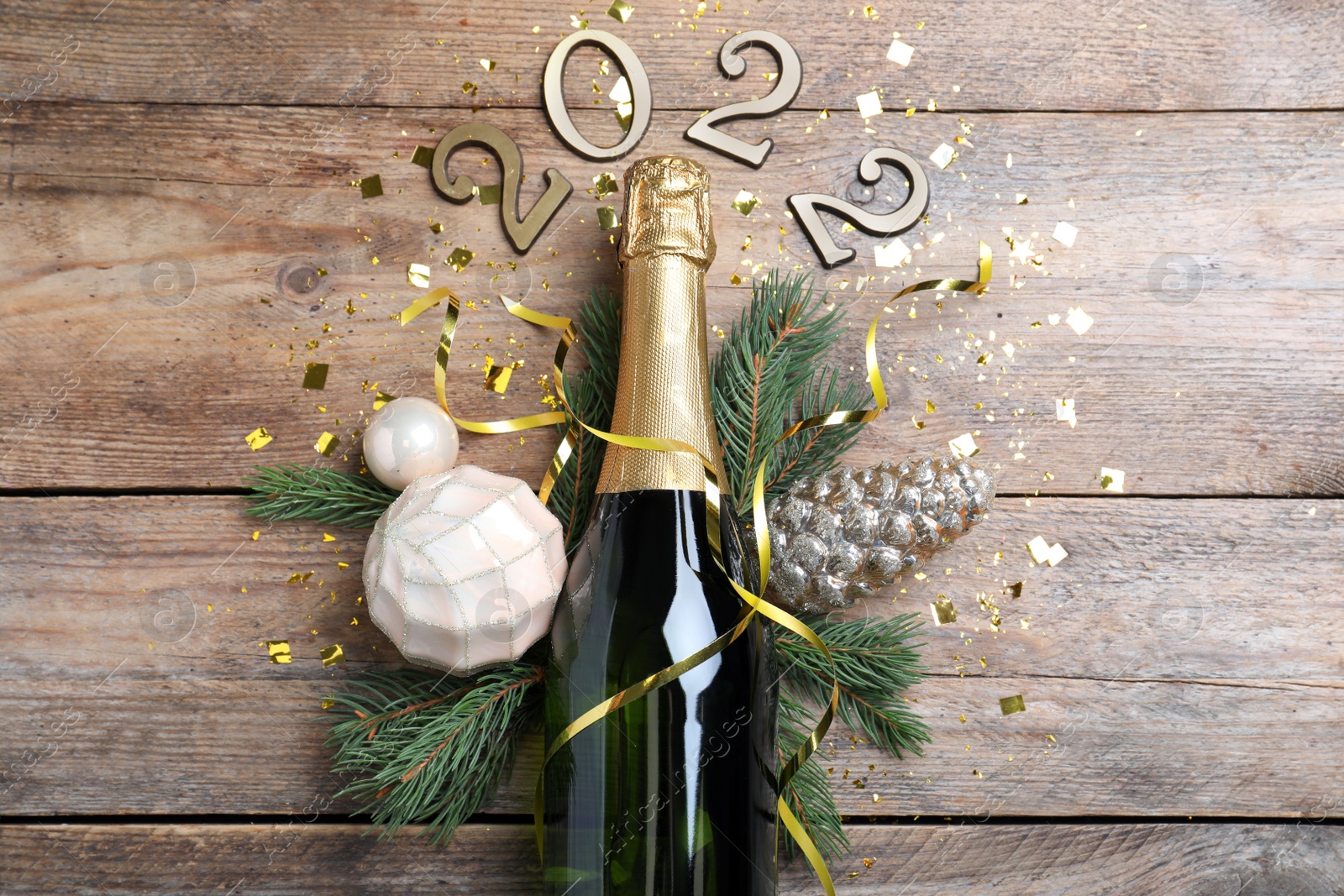 Photo of Happy New Year 2022! Flat lay composition with bottle of sparkling wine on wooden table