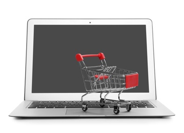 Photo of Internet shopping. Laptop with small cart isolated on white