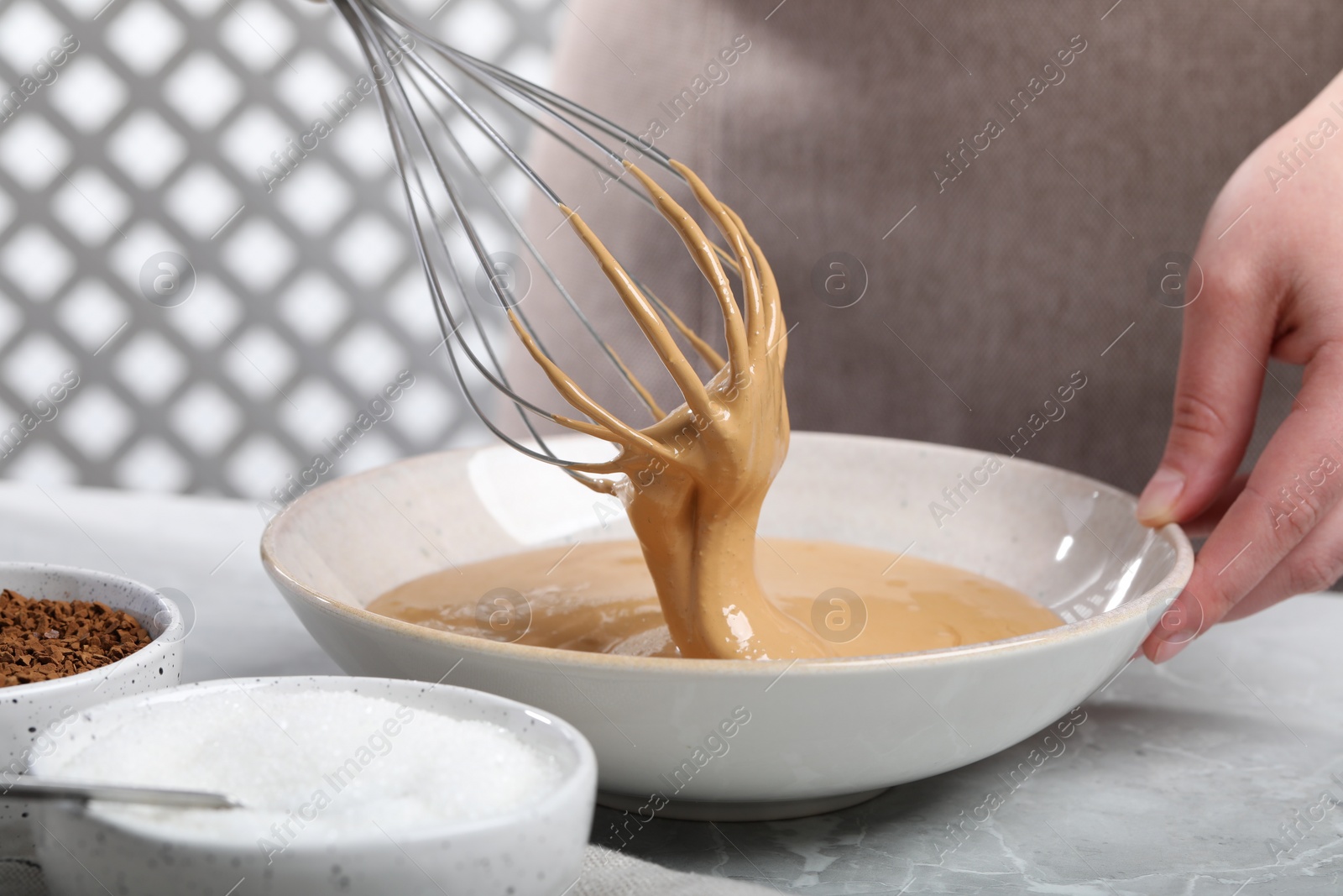 Photo of Woman whipping cream for dalgona coffee at light gray table, closeup