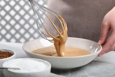 Woman whipping cream for dalgona coffee at light gray table, closeup