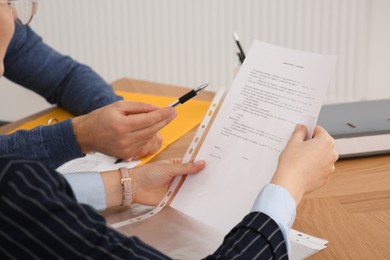 Businesspeople working with documents at wooden table in office, closeup