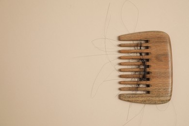 Wooden comb with lost hair on beige background, top view. Space for text
