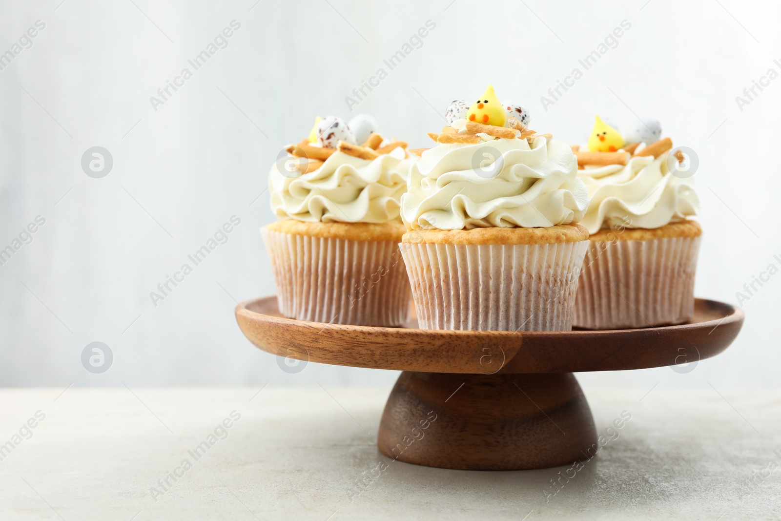 Photo of Tasty Easter cupcakes with vanilla cream on gray table, space for text